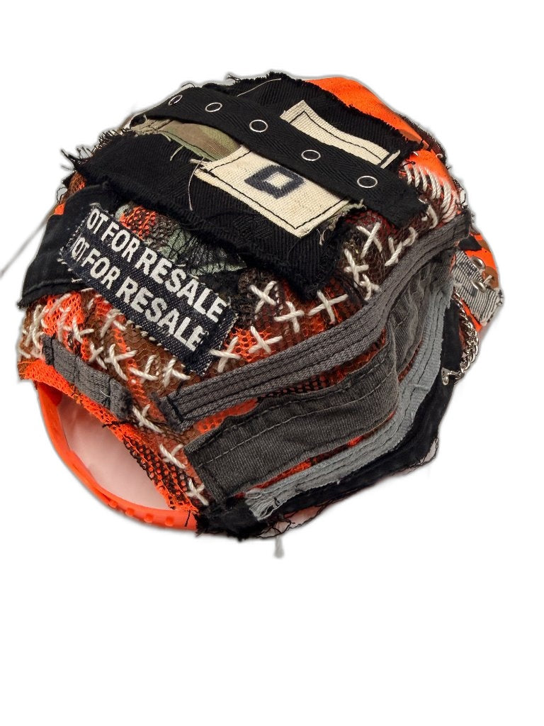 Crown view of orange camo cap showing X stitch lacing layered grey fabric strips NFR patch grommet strap and silver chain — one of one upcycled NFR LA