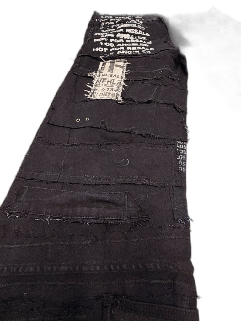 Detail of left leg showing NFR barcode patch double grommets horizontal raw seam panels and repeating LOS ANGELES NOT FOR RESALE screen print along inseam — one of one reconstructed NFR