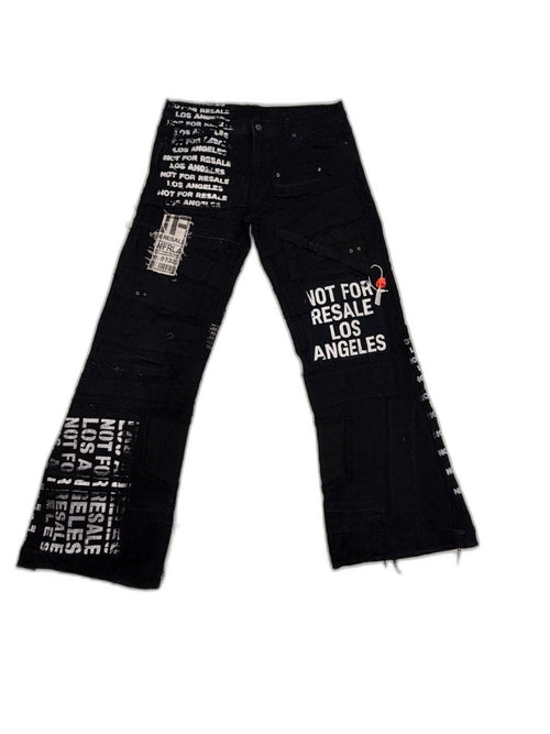 Front full view of black reconstructed stacked flare denim pants with large NOT FOR RESALE LOS ANGELES sewn patch NFR barcode label and all-over text along inseams — one of one NFR LA