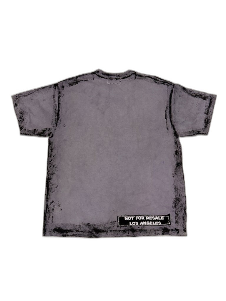 Back of grey smoke-dyed NFR tee showing clean grey surface with NOT FOR RESALE LOS ANGELES woven patch at lower right hem — one of one upcycled Not For Resale Los Angeles